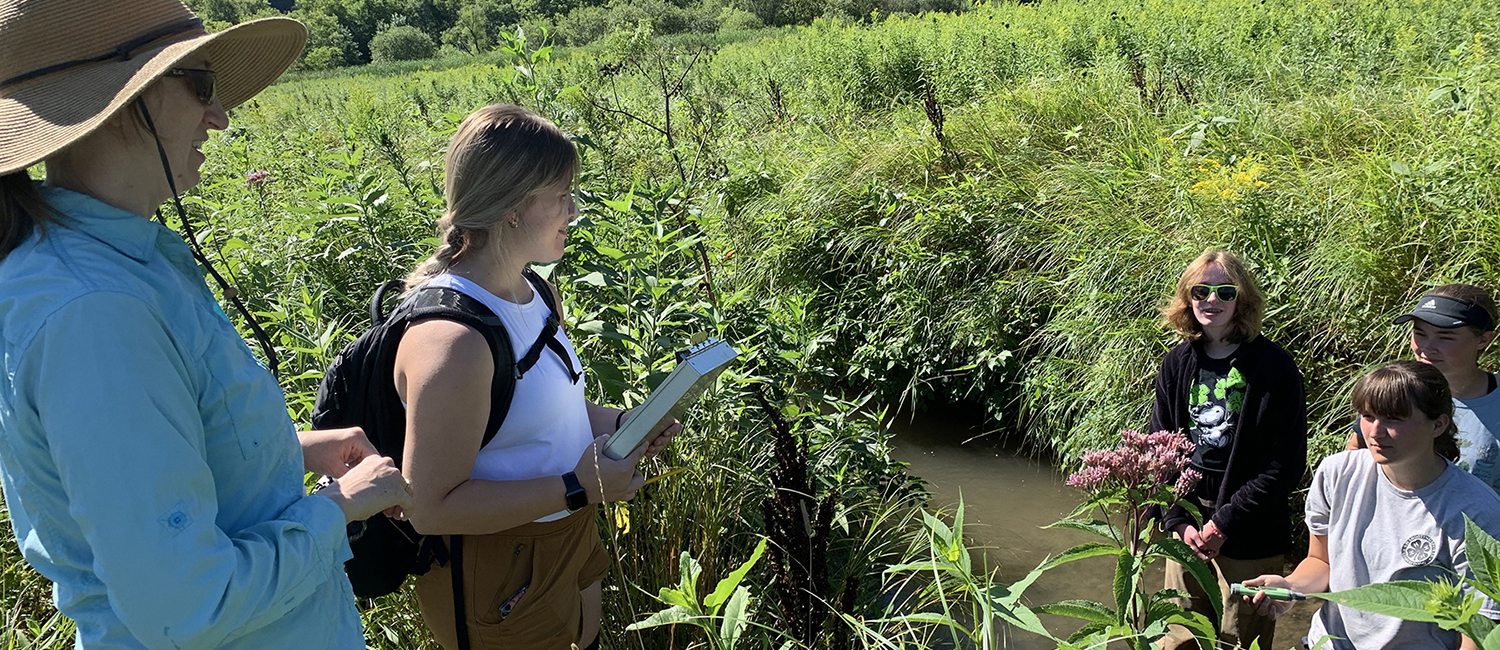 UW-Stout Assistant Professor Nicole Hayes, left, guides three high school students as they conduct tests on Gilbert Creek west of Menomonie. / UW-Stout