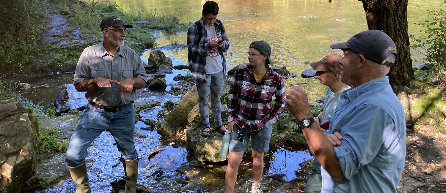 Students talk with water professions by river